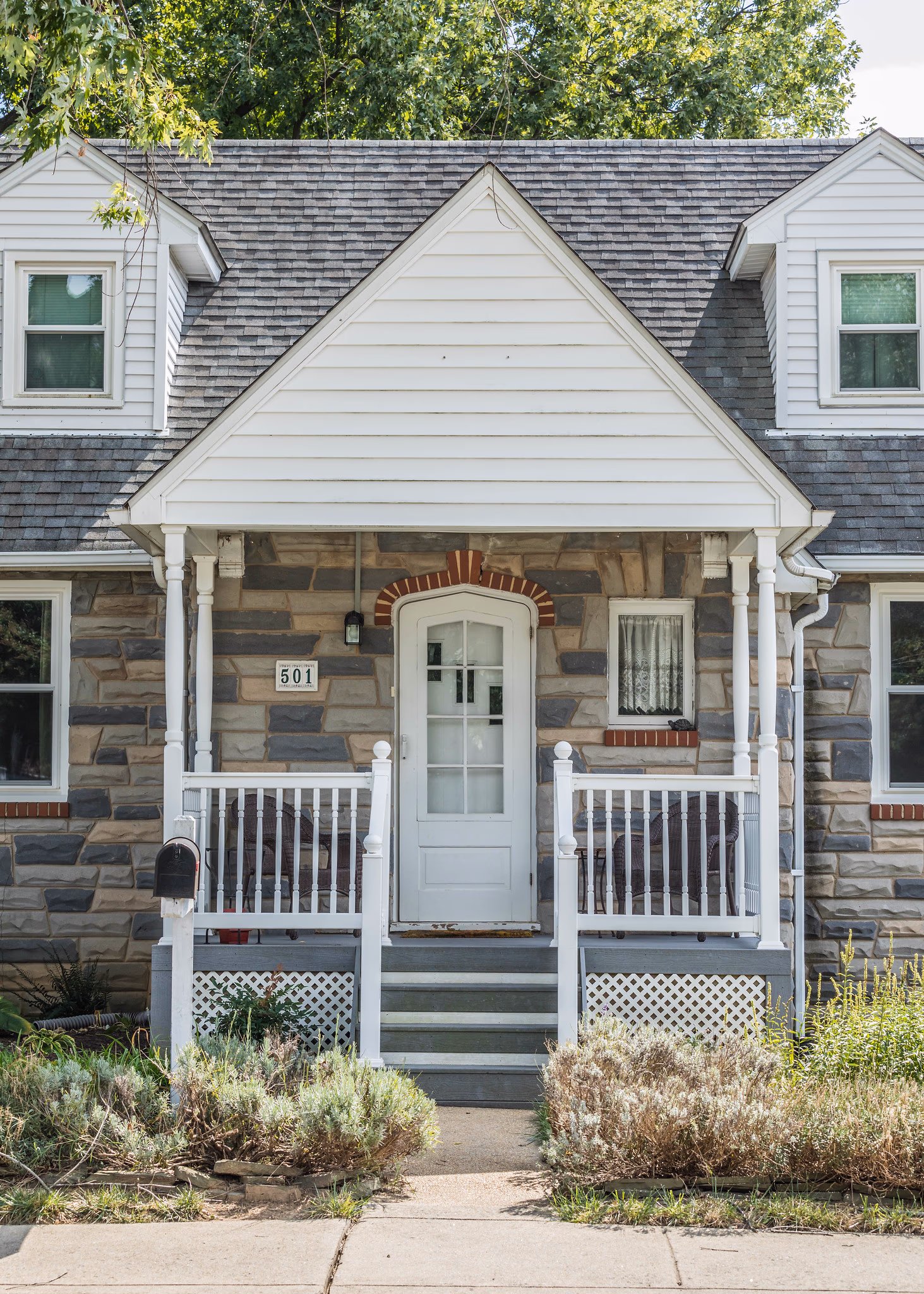 Front entry of a stone-faced cottage with a white gabled porch, Douglas County, Oregon